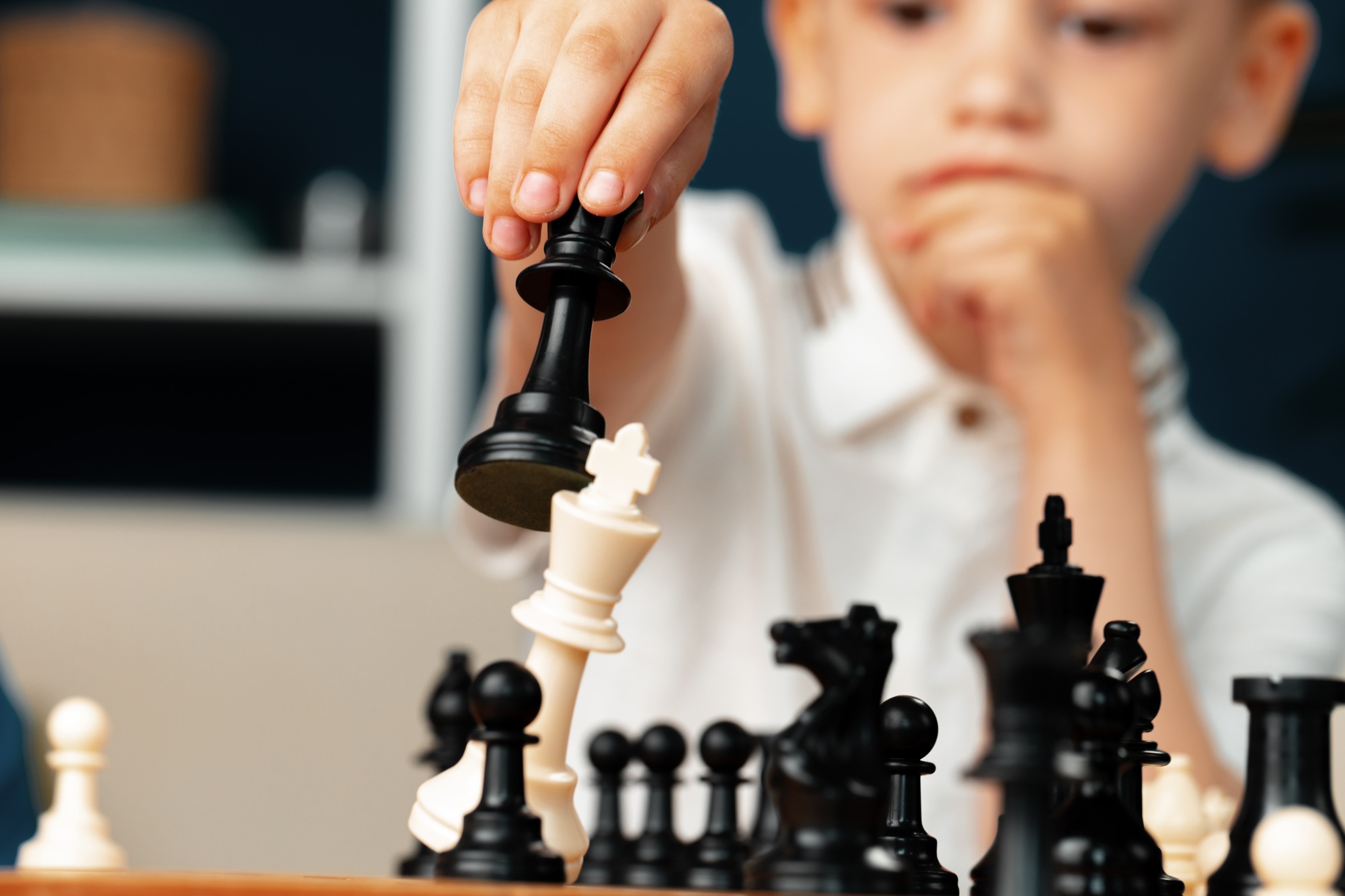 Close up photo of a little boy playing chess