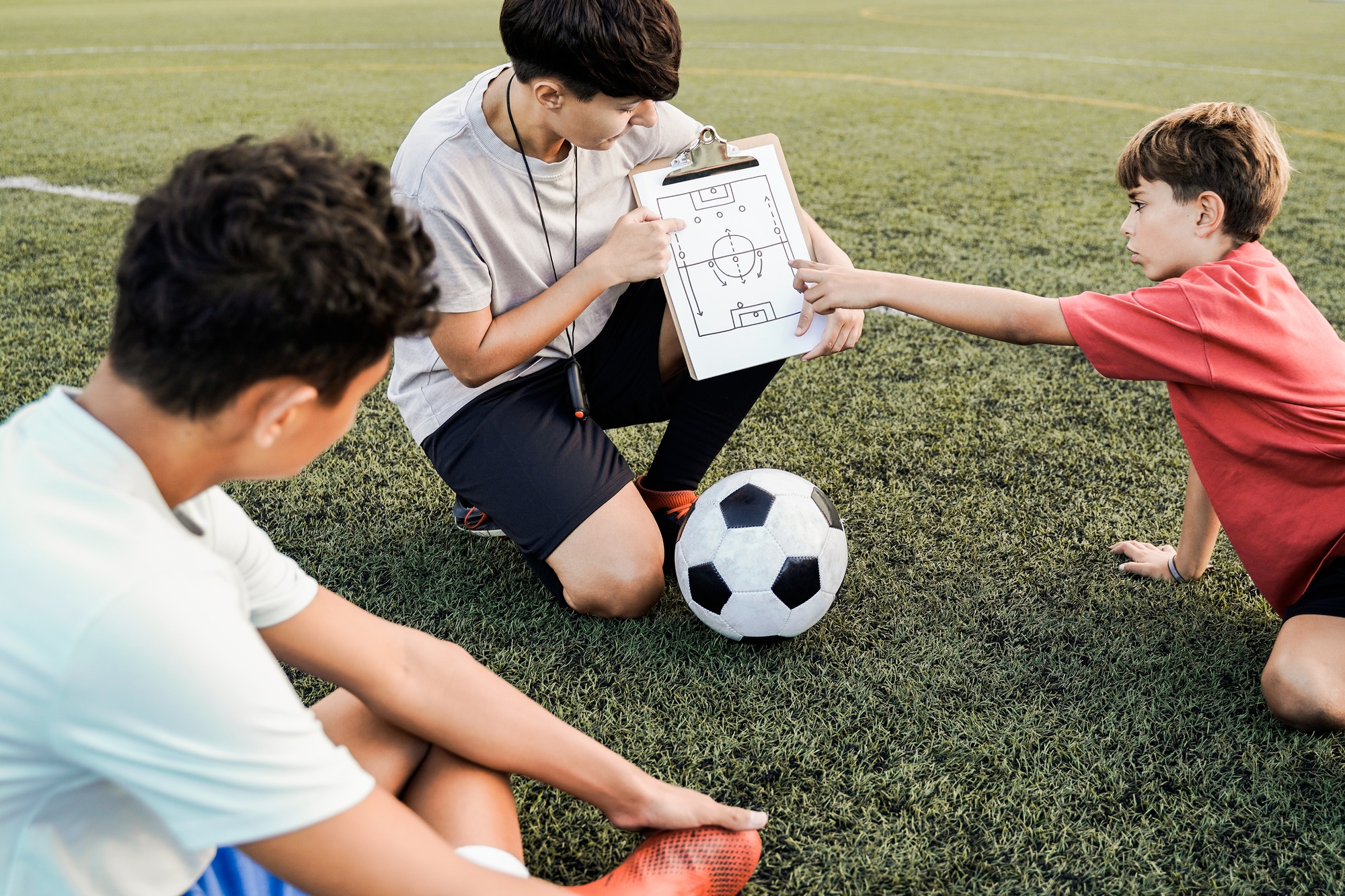 School children with coach teacher during sport training at soccer field - Fitness and educati